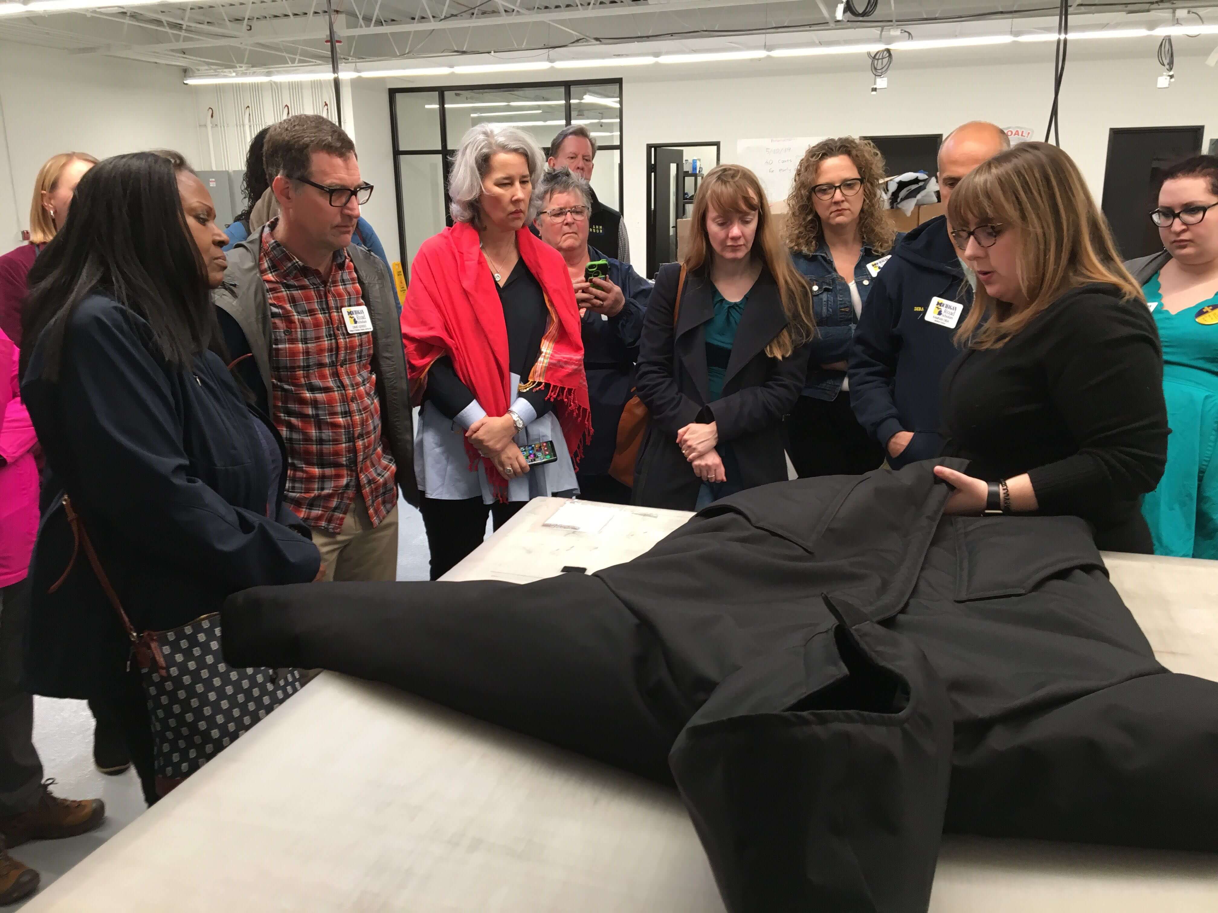 Michigan Road Scholars standing around a table with a jacket on it that a someone is holding and describing