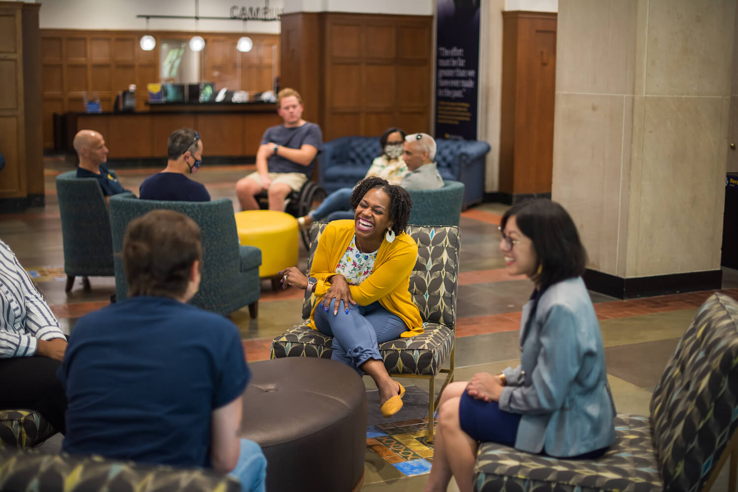 Photo of a diverse group of University of Michigan staff members talking and laughing in the Michigan Union