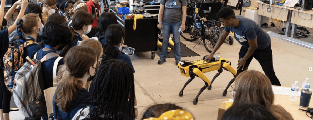 Masked students watching a demonstration from a person wearing a U-M Robotics t-shirt