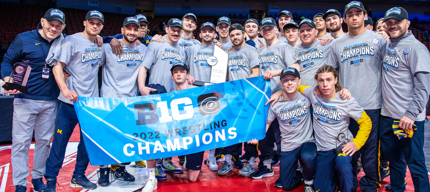 The wrestling team posing with a banner that says "Big 10 2022 Wrestling Champions"