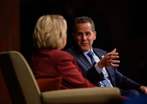 Michael Barr speaking on stage with Hillary Clinton